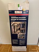 Photo of the unopened box of the wardrobe organizer system by Lee Rodman with product branding, warranty text, and closet storage images.