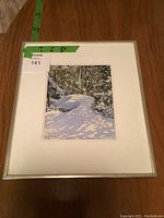 Full view of framed watercolor painting on wooden floor with measurement tape