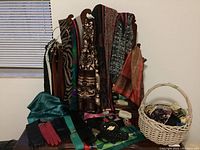 Full view of hanging scarves, belts on a rack, and gloves laid out on table surface