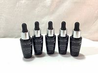 Front view of five identical black bottles with silver dropper caps labeled Lancôme Advanced Génifique Youth Activating Concentrate Serum.
