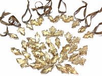 Photo showing multiple amber-colored Swarovski crystal snowflake-shaped ornaments and loose snowflake pieces with attached brown ribbons arranged on a white background.