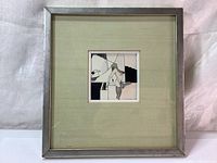 Framed artwork with silver metal frame and light green fabric matting, showing entire piece.