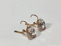 Pair of earrings showing side profile of rose gold lever back hooks and large solitaire cut crystals.