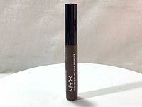 Full upright view of the NYX Tinted Brow Mascara tube showing the black cap and brown body with white branding text.