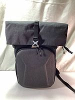 Front view of backpack with roll top folded and clasped, hard shell front compartment visible