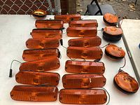 Top view showing 14 rectangular orange signal and side marker lights with amber lenses, and 5 round shaped lights grouped on a table surface.
