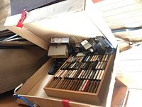 Photo of the open cardboard case showing numerous country music cassette tapes in a wooden holder and several VHS tapes inside the case.