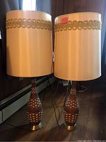 Two matching wood and brass table lamps with cream drum shades side by side