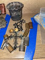 Overview of all items including miniature metal capsules, rosary beads, and child size cup