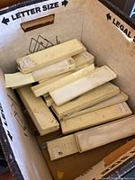 Long rectangular boxes in a cardboard bin likely containing pewter miniatures or collectibles.