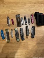 Overview of all pocket knives and accessories laid out on wooden surface showing variety and condition.