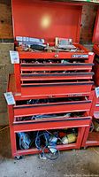 Overall view of red Craftsman tool chest with multiple drawers and bottom shelf of power tools