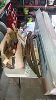 Antique wooden yoke parts, hand tools in cardboard box with painting supplies visible on white table