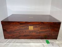 Front view of closed box showing flamed mahogany surface and brass key escutcheon.