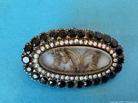 Front view of brooch showing woven hair design under beveled glass with pearl and jet stone borders