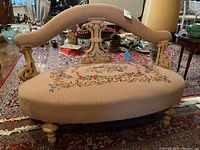 Full front view of settee showing carved wood frame, curved backrest and oval tapestry seat.