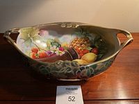 Oval porcelain fruit bowl with hand painted fruit detail inside and green gold floral exterior, shown from front view
