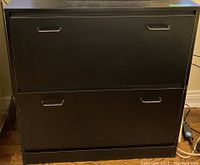 Front view of the black IKEA shoe cabinet with two pull-down drawers closed.