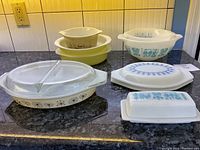 Three mixing bowls (brown wheat pattern, two solid yellow) and two covered casseroles at rear (Butterprint and yellow) plus front divided and oval dishes