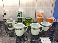 Overview of all mugs showing various green, orange and blue printed patterns and one textured green glass mug