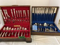 Two wooden boxes side by side filled with silver-plated flatware.