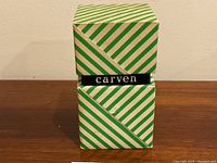 Closed green and white striped box showing black band with 'carven' logo