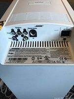 Rear panel of Bose PS18 HD powered speaker system showing speaker outputs, media center input, AC power inlet, model and serial number label.