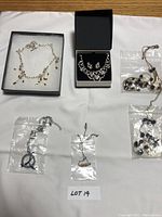 Overview of all six costume jewelry items including necklaces, earrings, and bracelet in separate compartments and bags.