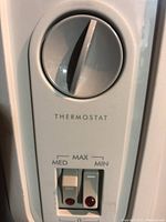 Close-up of thermostat dial and two heat level switches with indicator lights on the heater.