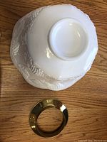 Bottom view of the milk glass punch bowl showing the embossed grape design and gold metal ring base.