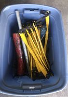Blue plastic tub with yellow plastic tire chains, a red and metal tube, and a blue bottle jack inside
