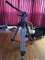 Full view of the Ravelli video camera tripod with adjustable legs, lever for camera movement, and attached quick release plate.