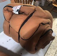 Rolled up brown padded sleeping bag showing thickness and durable material with some wear