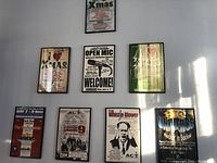 Eight rectangular black metal concert poster frames; various posters with text and graphics.