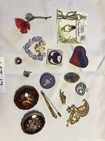 Photo showing a collection of 14 various pins including floral, fish, heart designs, and gold-tone costume jewelry pins.
