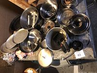 Overview of all camping cooking supplies including pots, pans, lids, utensils, and gas burners on a table.