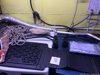 Photo showing black rubber floor mat, ropes, and part of flexible vent hose, placed on top of white appliance.