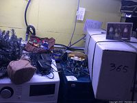 Photo showing assorted Christmas decorations including a metal tree stand, ornaments and garlands placed on and around a microwave and other household items.