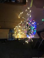 White bulb Christmas lights tangled and draped on spool sitting on table.