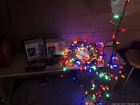 Multi-colored Christmas lights lit on a table, tangled string visible