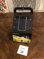 Front view of Zareba electric fence controller showing solar panel and label with specifications and controls.