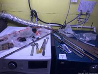 Photo showing various hand tools including open-end wrenches, screwdriver, and hacksaw placed on and around a washing machine and a tool chest.