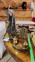 Photo showing brass inkwell set, brass bookends, and metal abstract sculpture on table