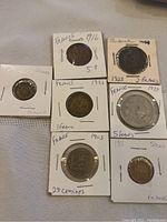 Photo showing all seven French coins individually mounted in protective holders with visible inscriptions and dates ranging from 1903 to 1939.