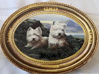 Front view of oval decorative plate showing two West Highland White Terriers in a natural setting, the artwork titled 'In the Heather'.