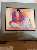 Image of a 5x5 inch colorful art tile by RC Gorman showing a stylized reclining woman in a purple and red striped top and light blue pants, mounted on a beige backing.