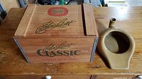Wooden John Labatt Classic beer crate and vintage stoneware bedpan on wooden surface
