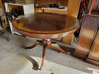 Full side view of the vintage reproduction mahogany round table with glass top, showing overall condition and style.