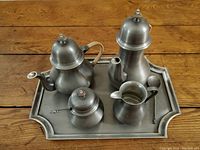 Full view of the seven-piece vintage pewter tea and coffee service on the tray on wooden floor