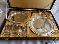 Overall view of vintage snack tray set including glass jars, forks, relish dish, and two metal dishes presented in original satin-lined box.
